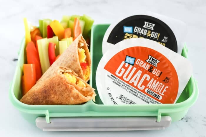 Lunchbox with veggie egg wrap, colorful bell pepper and celery sticks, and two &iexcl;Yo Quiero! Grab & Go dips&mdash;guacamole and bean dip.