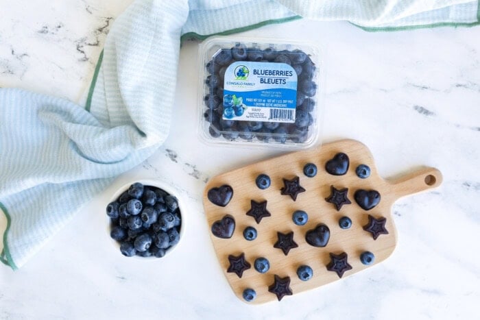 Fresh Consalo blueberries and homemade blueberry gummies on a wooden cutting board.